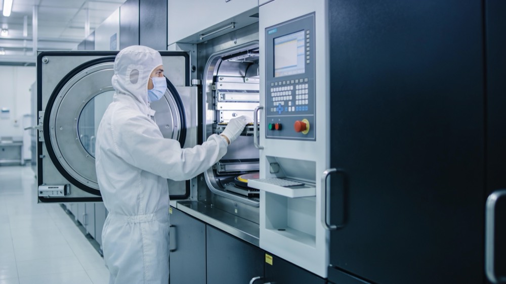 A gowned operator loading a process tool in a cleanroom